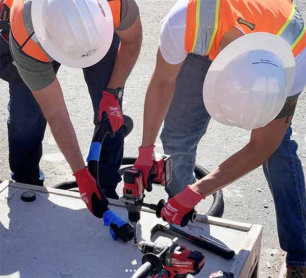 Journeyman using a drill and another worker with a vacume on the job..